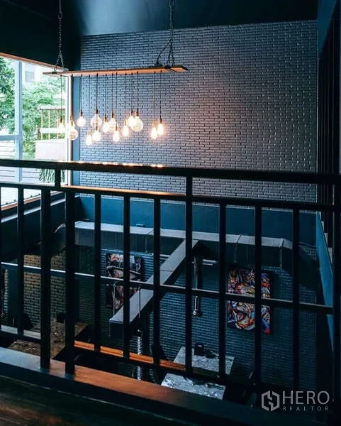 Detached House for rent in Watthana, Bangkok - Double-height landing with pendant lights, metal railing and brick feature wall overlooking greenery.