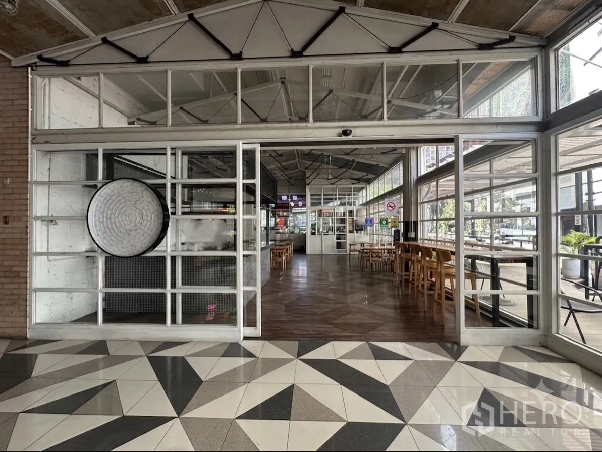 零售空间 for rent in Watthana, Bangkok - 转角玻璃门面与滑动门入口，挑高空间，可见街景。