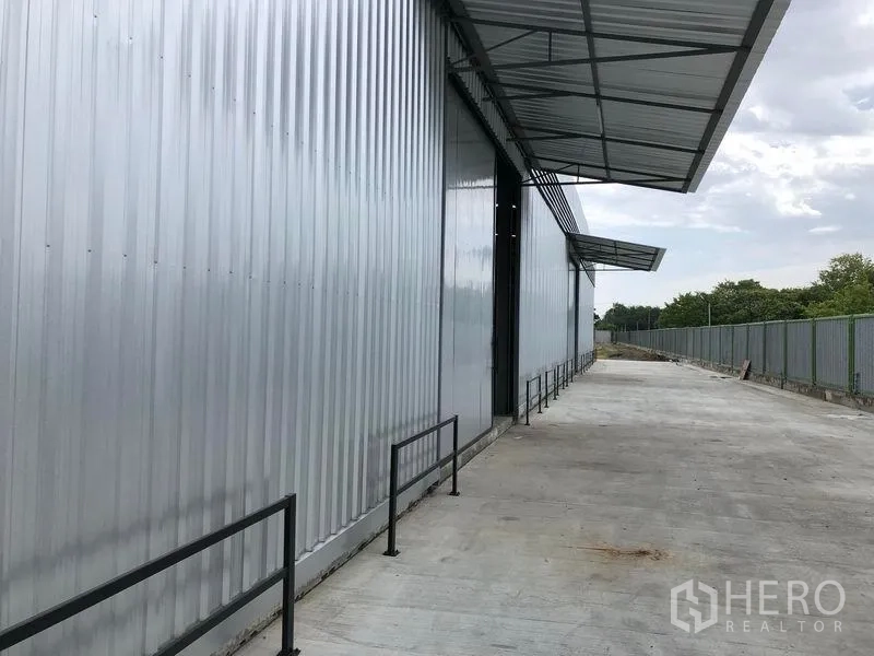 货栈 出租在Pathum Thani - 仓库外立面沿线的有顶装卸走道，配安全护栏与围栏。
