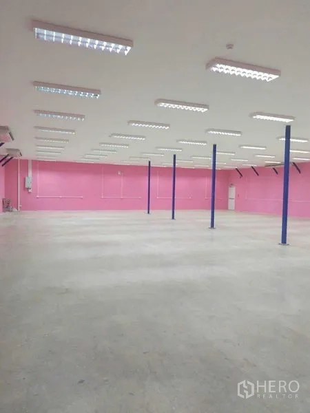 Warehouse for rent in Khlong Luang, Pathum Thani - Open-plan warehouse interior with LED lighting, blue columns and concrete floor.