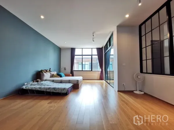 Townhouse for sale - Spacious master bedroom with hardwood floors, large windows and a black-framed glass partition.