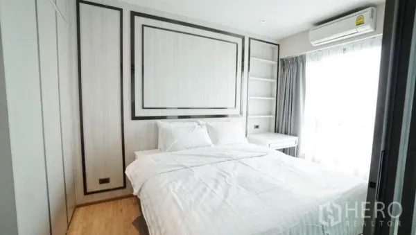 Condominium for sale in Khlong Toei, Bangkok - Cozy bedroom with queen bed, built-in wardrobe and shelving, air conditioner and sheer-curtained window.