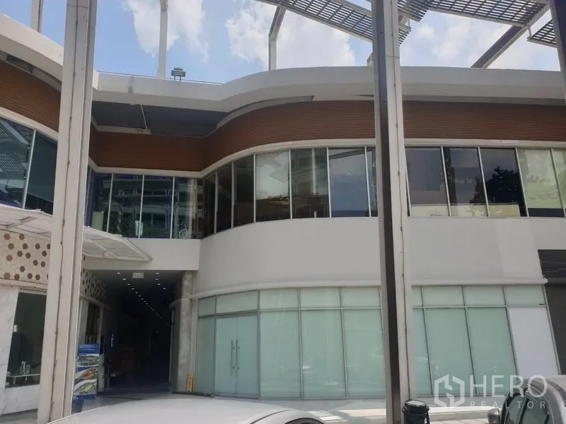 零售空间 出租在Khlong Toei, Bangkok - 澎蓬区域现代商业建筑外立面，弧形玻璃与一层店面。