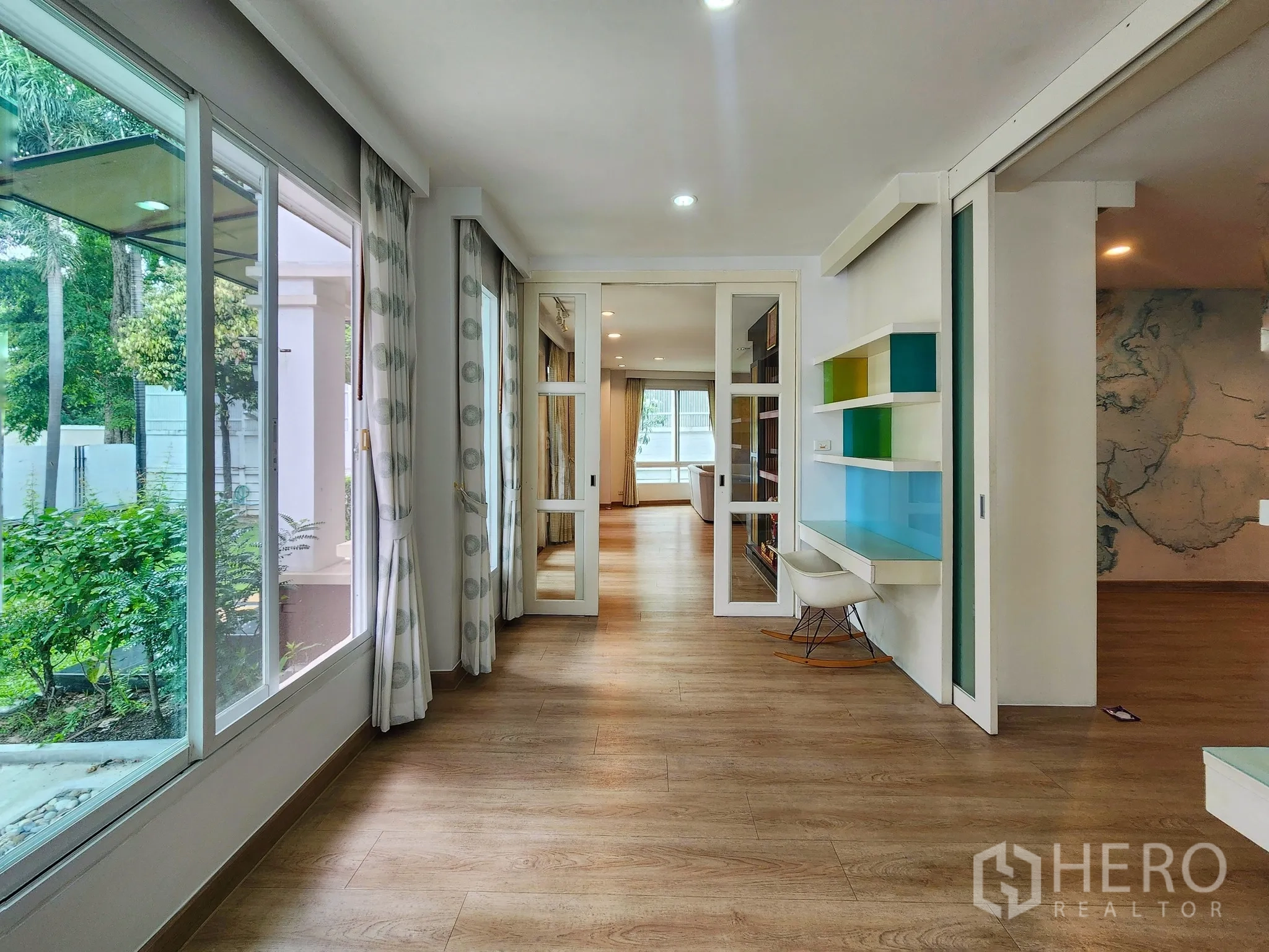 Detached House for rent in Bang Kapi, Bangkok - Glass-lined corridor with built-in desk and colorful shelving overlooking the garden.