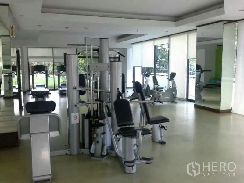 Condominium for rent in Watthana, Bangkok - Well-equipped fitness room with weight machines, cardio equipment and mirrors overlooking the garden.