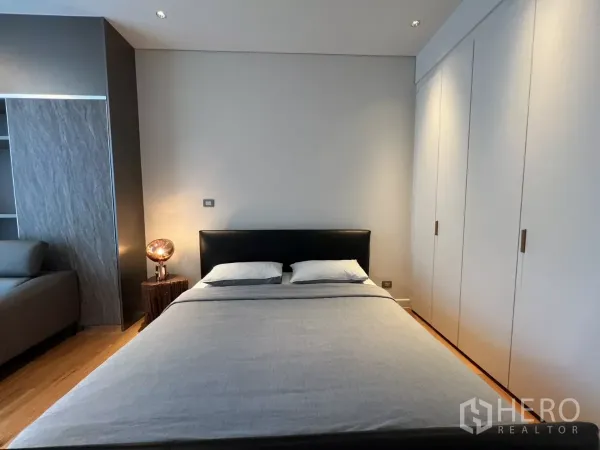 公寓 出租在Pathum Wan, Bangkok - 极简卧室，软包床头与白色嵌入式衣柜。