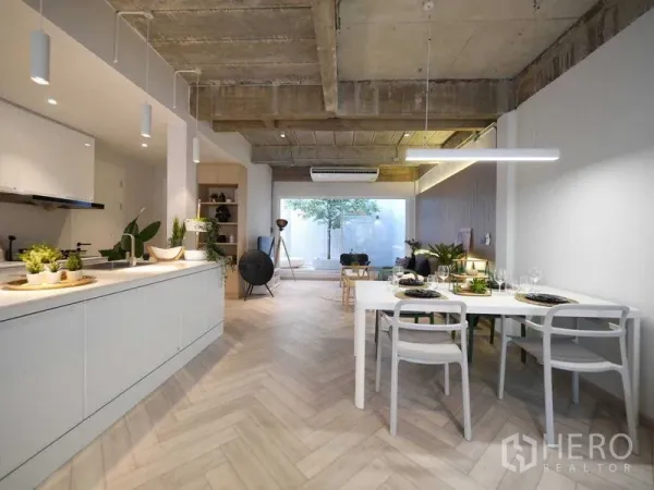 Townhouse for rent in Watthana, Bangkok - Open-plan living, dining and kitchen with herringbone floors, concrete ceiling and large rear window.