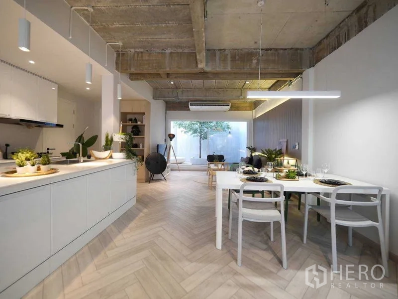 Townhouse for rent in Watthana, Bangkok - Open-plan living, dining and kitchen with herringbone floors, concrete ceiling and large rear window.