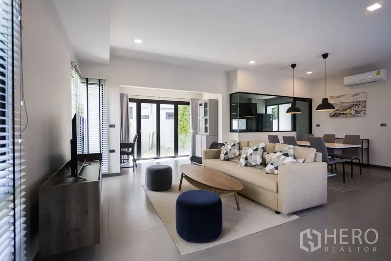 Townhouse for rent in Samut Prakan - Bright open-plan living and dining area with sliding glass doors and pendant lights.