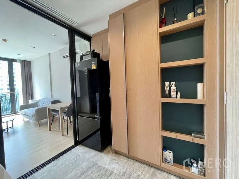 公寓 出租或出售在Watthana, Bangkok - 入户区带高柜与开放格架，望向客厅与阳台。