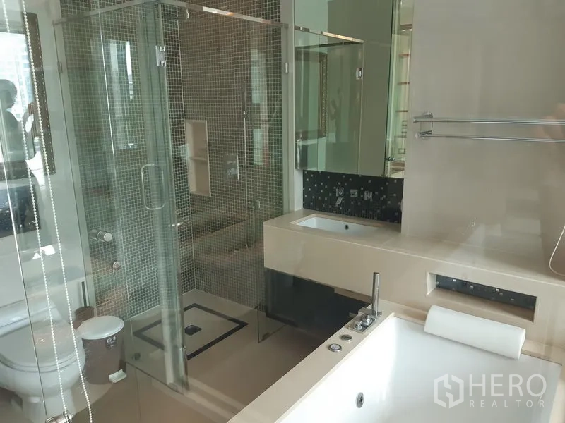 Condominium for rent in Khlong Toei, Bangkok - Spacious bathroom showing separate rain shower, toilet and countertop sink beside the bathtub.