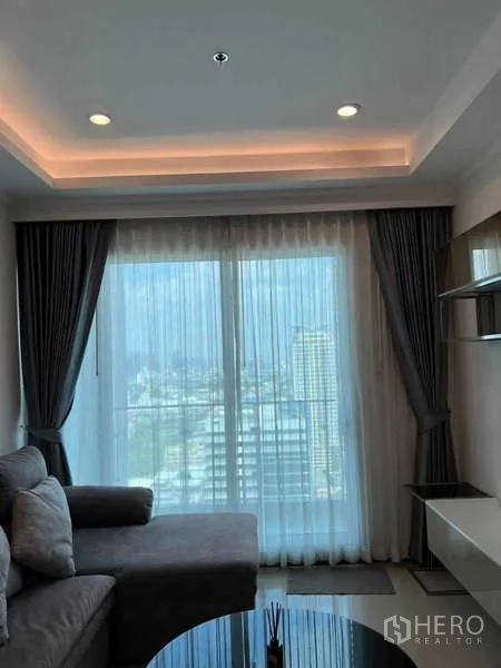 公寓 出租在Ratchathewi, Bangkok - 客厅落地玻璃与窗帘，转角沙发舒适温馨。