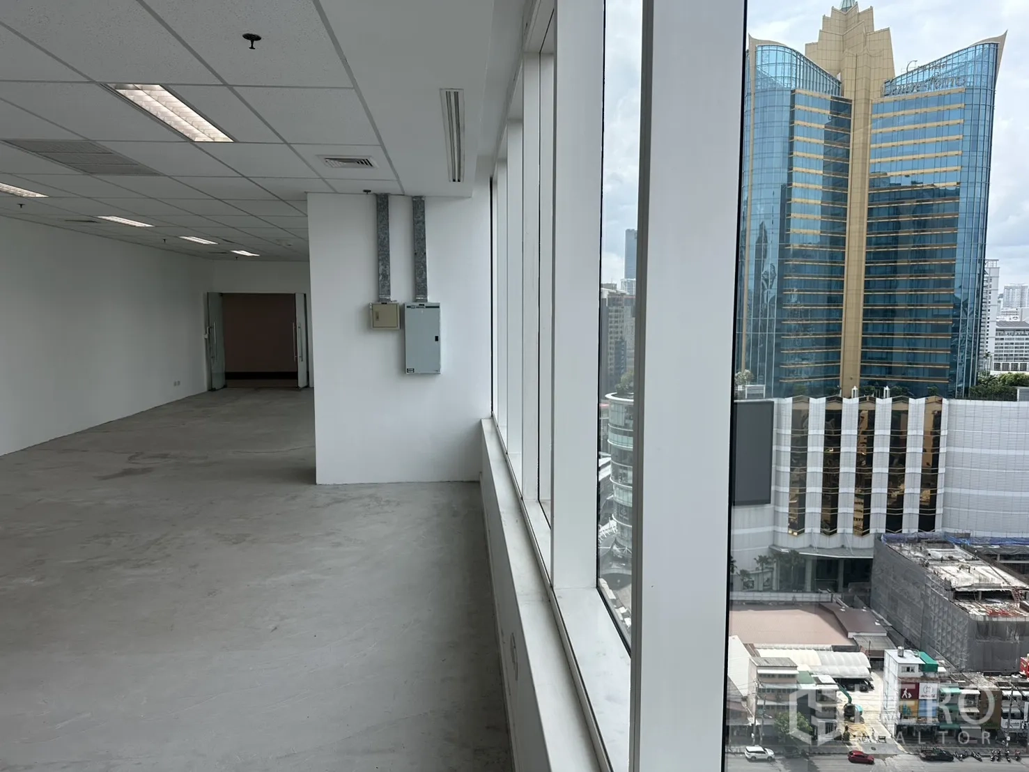 办公室 for rent in Watthana, Bangkok - 沿窗的办公走道，可见窗外高层建筑。