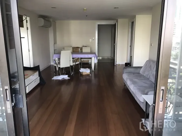 公寓 出租或出售在Watthana, Bangkok - 从阳台望入的开放式客厅，木地板、灰色沙发与餐桌。