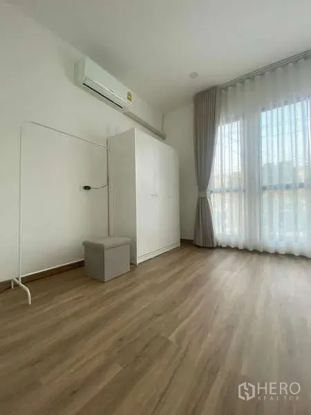 Townhouse for rent in Bang Kapi, Bangkok - Spare room with white wardrobe, air conditioner and tall curtained window.