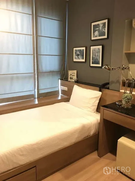Condominium for rent in Sathon, Bangkok - Second bedroom with single bed, built-in desk, wall art and soft natural light.