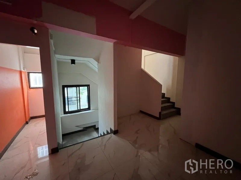 Shophouse for rent in Watthana, Bangkok - Stair landing with marble-look tiles, window light, and stairs connecting upper levels.