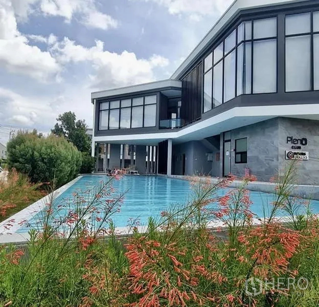 Townhouse for rent in Bang Phli, Samut Prakan - Estate clubhouse with large outdoor swimming pool and glass‑fronted building.