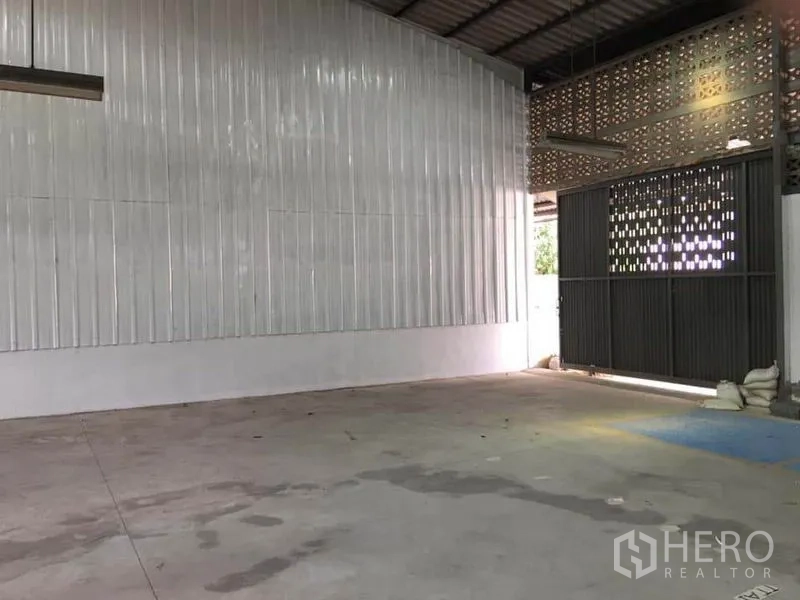 Warehouse for rent in Samut Prakan - Warehouse bay with corrugated metal wall, ventilation blocks and wide entry.