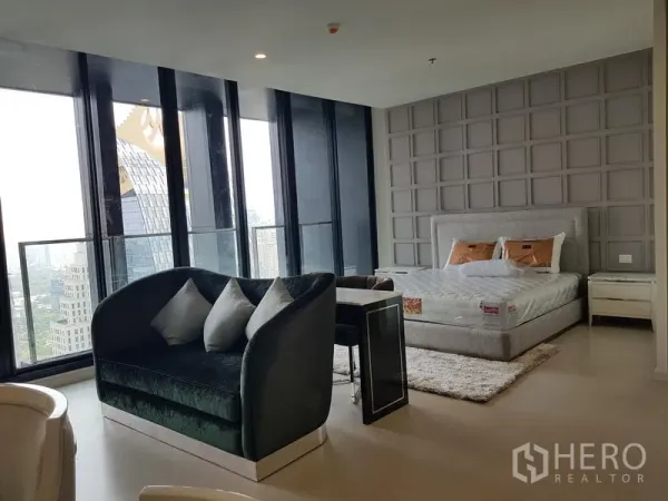 公寓 出租在Pathum Wan, Bangkok - 宽敞套房式卧室，设沙发、格纹装饰墙与落地窗观景