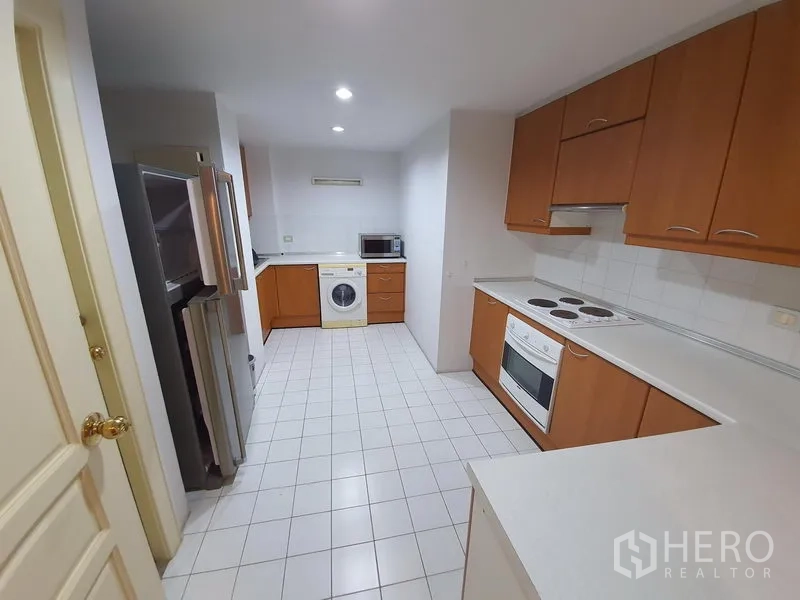 Condominium for rent in Pathum Wan, Bangkok - Enclosed kitchen with oven, electric cooktop, fridge, microwave, and washing machine.
