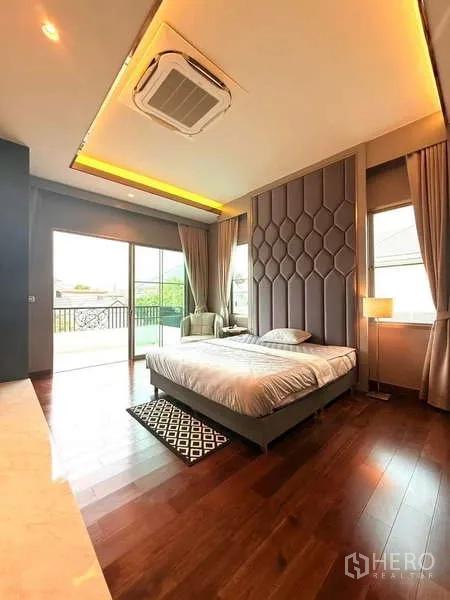 Detached House for rent or sale in Bang Phli, Samut Prakan - Bedroom opening to a balcony via sliding glass doors, tall headboard and timber flooring.