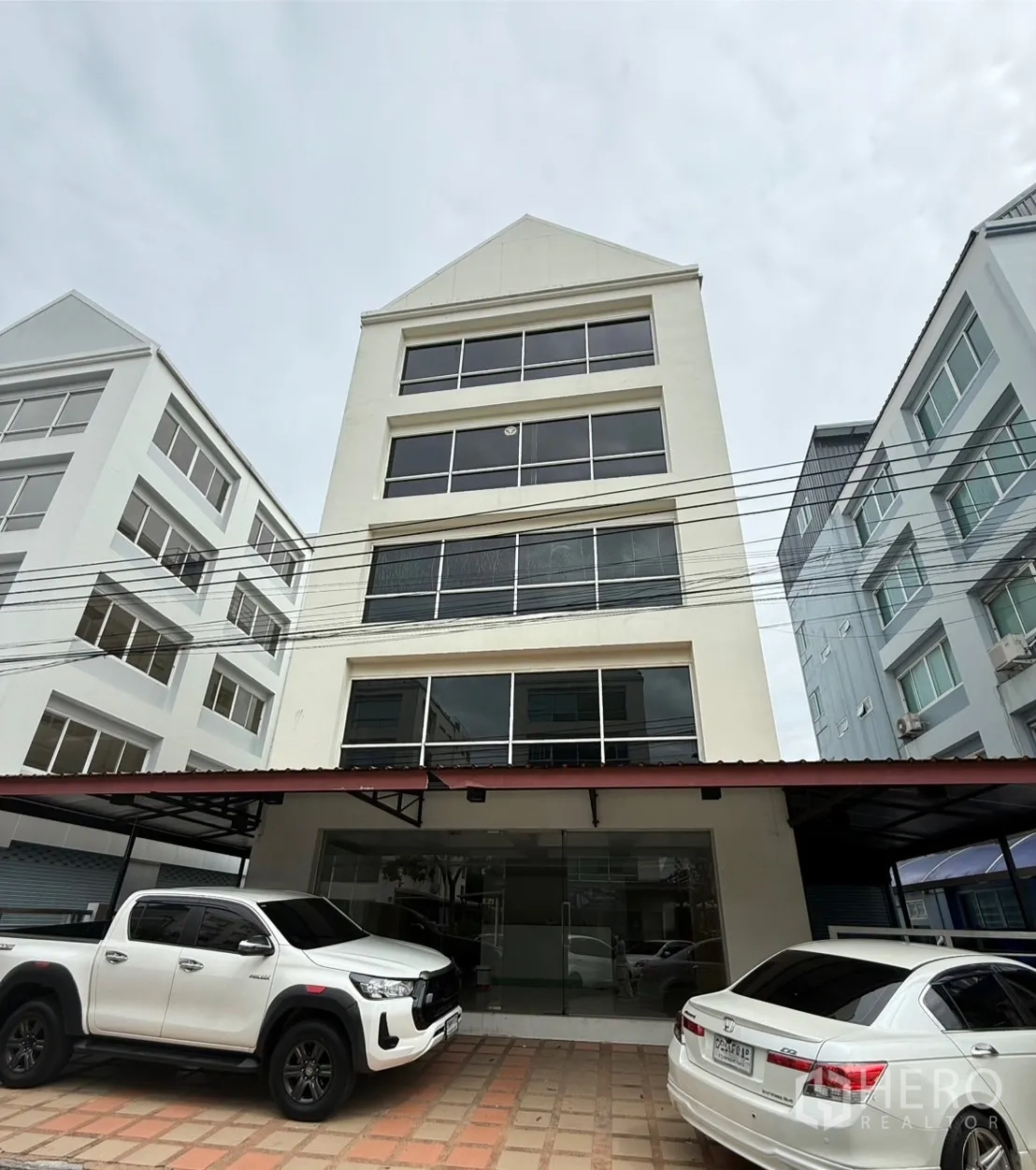 办公空间 出租在Bueng Kum, Bangkok - 多层办公楼正立面，带前方车位与玻璃入口。