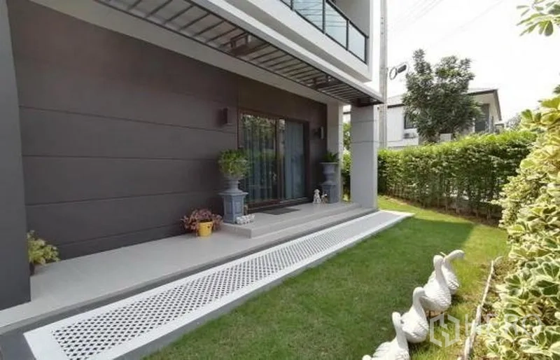 Detached House for sale in Bang Phli, Samut Prakan - Covered front porch with sliding glass doors and a small lawn bordered by hedges.