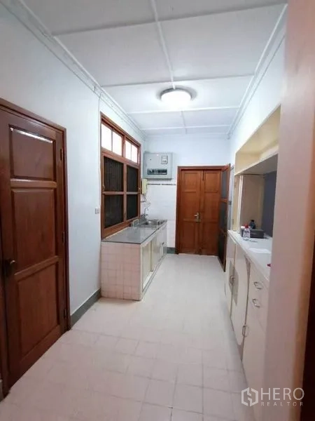 独立式住宅 出租在Pathum Wan, Bangkok - 走廊式厨房，不锈钢水槽、瓷砖台面与木门