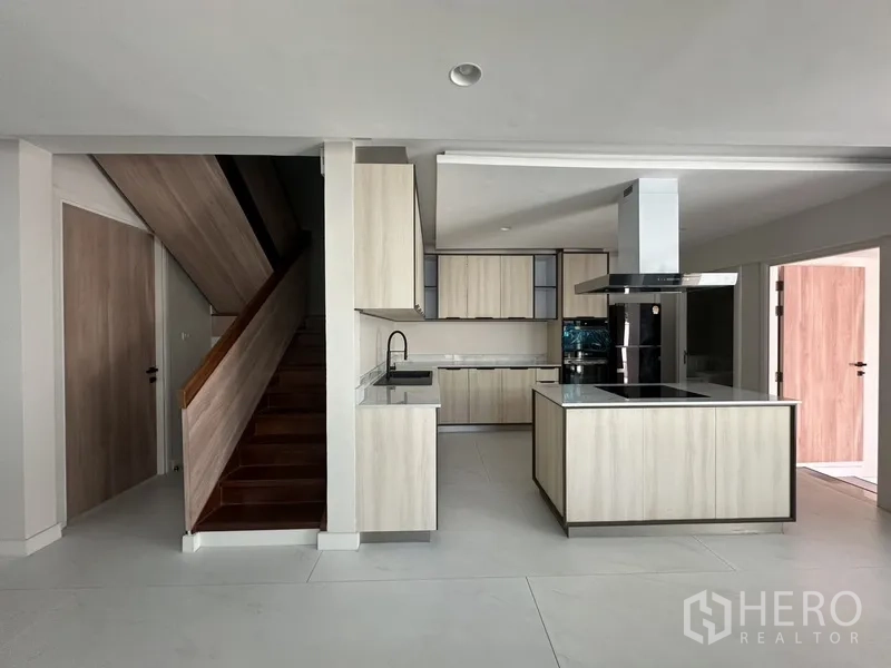 联排别墅 出租在Watthana, Bangkok - 开放式厨房餐厅视角，可见中岛与楼梯