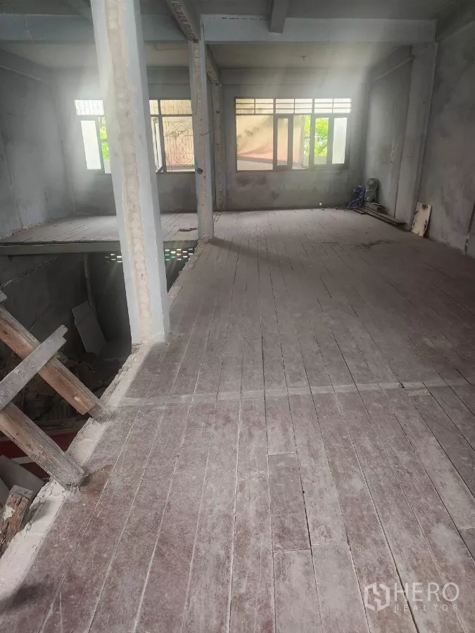 Shophouse for rent in Watthana, Bangkok - Upper-floor open plan room with large windows and a wood floor under renovation.