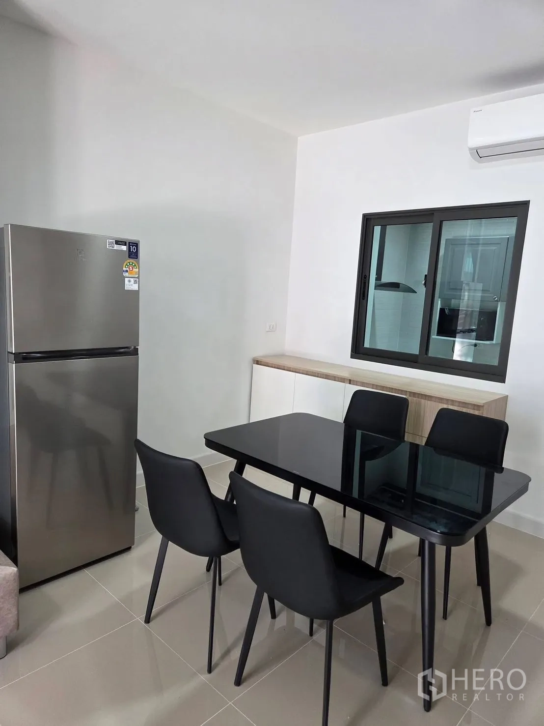 ทาวน์เฮาส์ for rent in Bang Phli, Samut Prakan - มุมทานอาหารโต๊ะกระจกสีดำ 4 ที่นั่ง ข้างตู้เย็นสแตนเลสและเครื่องปรับอากาศ