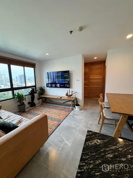 Condominium for rent or sale - Living room from the kitchen showing TV wall, large window, and dining set.
