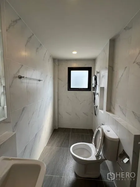 Detached House for rent in Bang Phli, Samut Prakan - Long bathroom with shower, toilet and gray floor tiles.