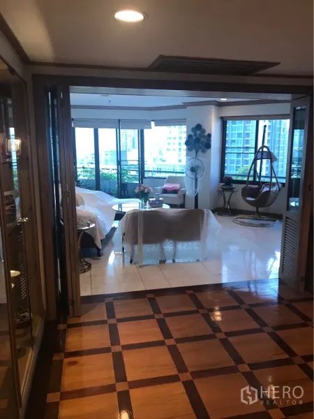 公寓 出租或出售在Watthana, Bangkok - 入口玄关带格纹木地板，通向采光充足的客厅与阳台绿植。