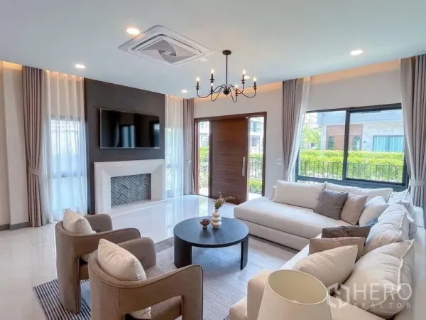 บ้าน ให้เช่าหรือขายในBang Phli, Samut Prakan - ห้องรับแขกพร้อมผนังตกแต่ง ทีวี โต๊ะกาแฟทรงกลม และหน้าต่างบานใหญ่