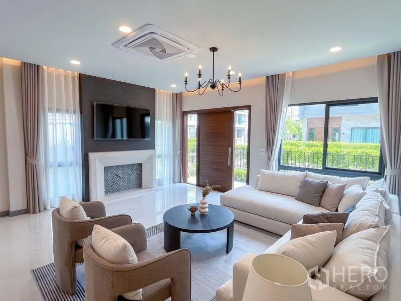 บ้าน ให้เช่าหรือขายในBang Phli, Samut Prakan - ห้องรับแขกพร้อมผนังตกแต่ง ทีวี โต๊ะกาแฟทรงกลม และหน้าต่างบานใหญ่