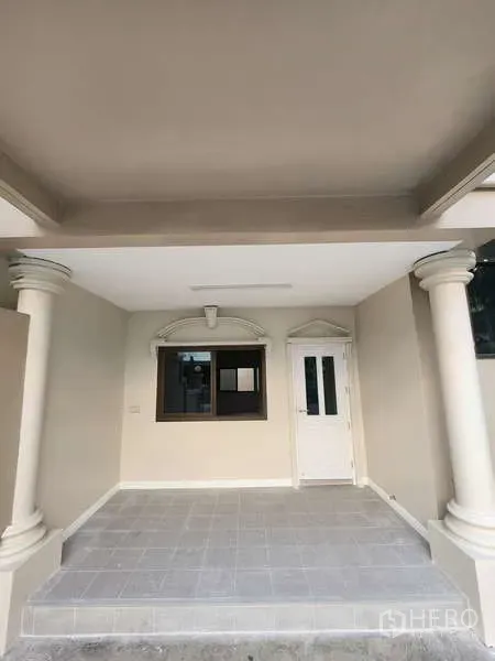 联排别墅 出租在Wang Thonglang, Bangkok - 带顶前院车位与入户门廊，立柱和白色门。