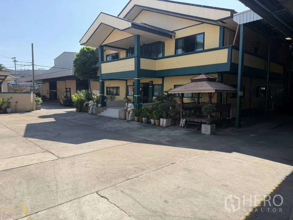 Factory for rent in Bang Phli, Samut Prakan - Office block with green trim and garden, next to a shaded gazebo.