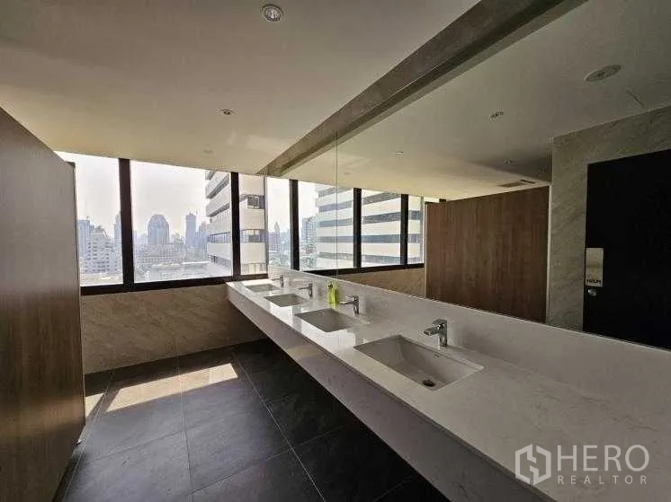 Office Space for rent in Bang Rak, Bangkok - Restroom with city-view windows, long countertop sinks, and dark floor tiles.