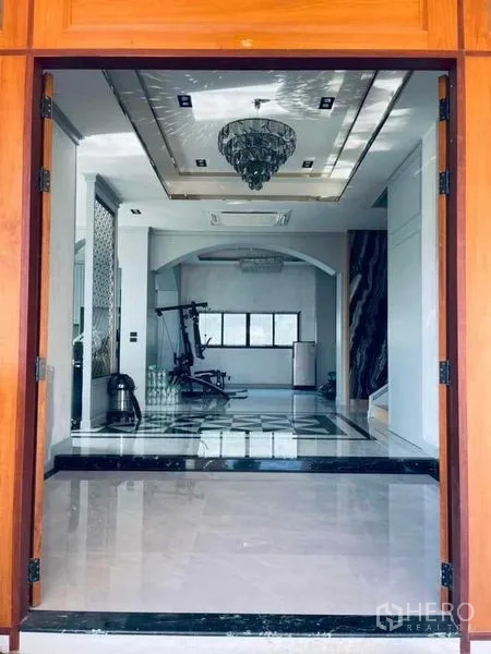 独立式住宅 出售在Mueang Nonthaburi, Nonthaburi - 入户门厅，亮面地砖与吊灯，通过拱门可见健身角落。