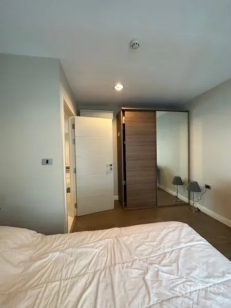 Condominium for rent in Khlong Toei, Bangkok - Bedroom with mirrored sliding wardrobe and bedside lamps.