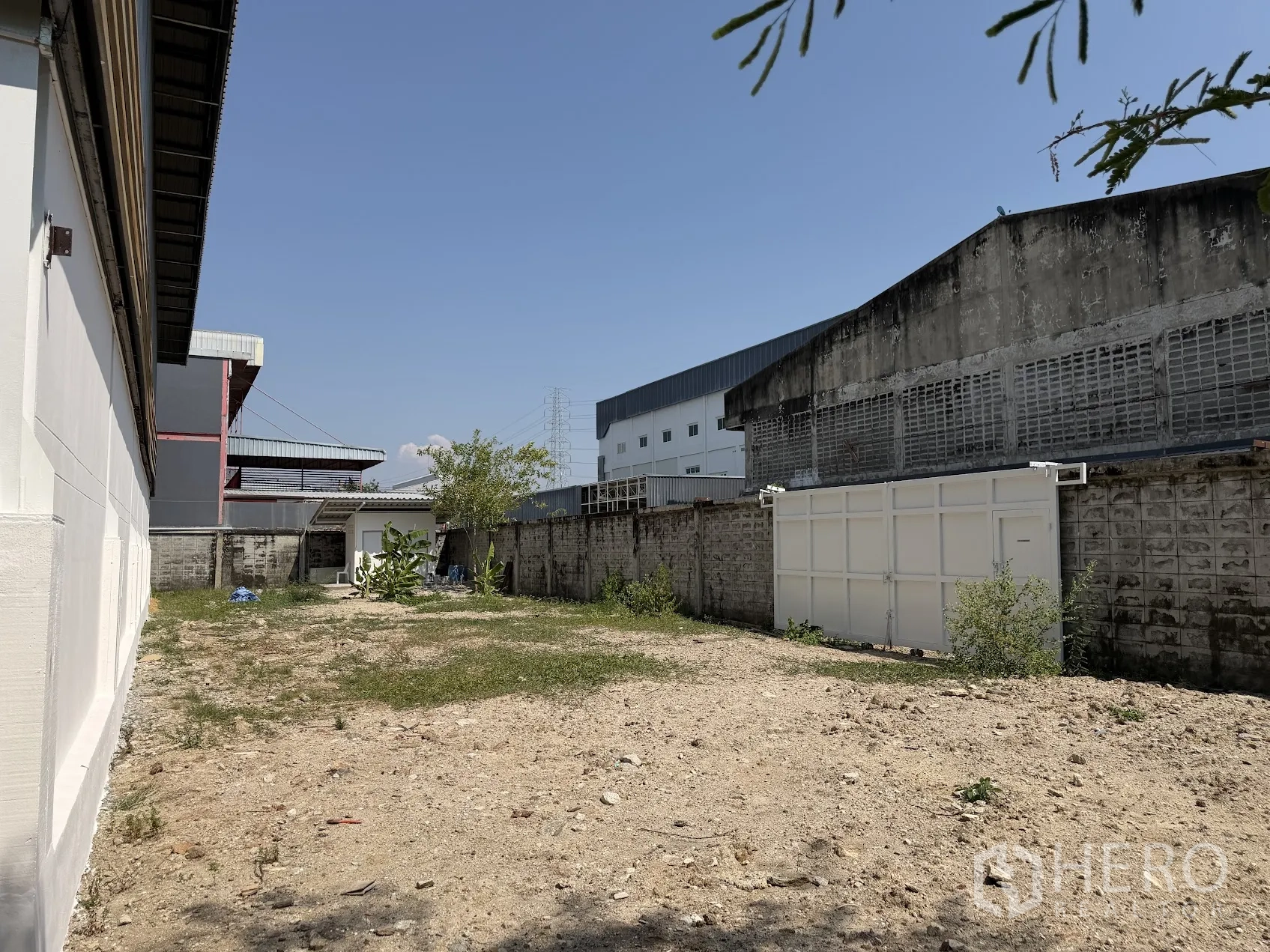 โรงงาน for rent in Bang Sao Thong, Samut Prakan - ลานด้านข้างมีกำแพงรั้วและประตูเหล็ก พื้นดิน มีศาลาเล็กข้างอาคารโรงงาน