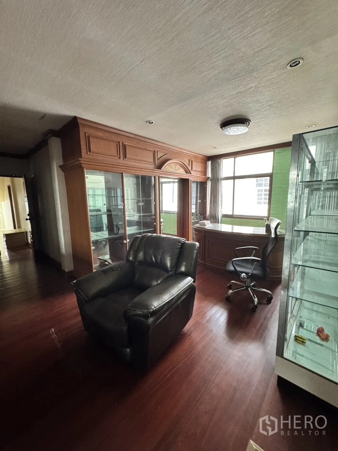 โฮมออฟฟิศ for rent in Watthana, Bangkok - ห้องทำงานบิวท์อินหน้าต่างมุมโค้ง เก้าอี้หนัง และตู้กระจกโชว์ของ