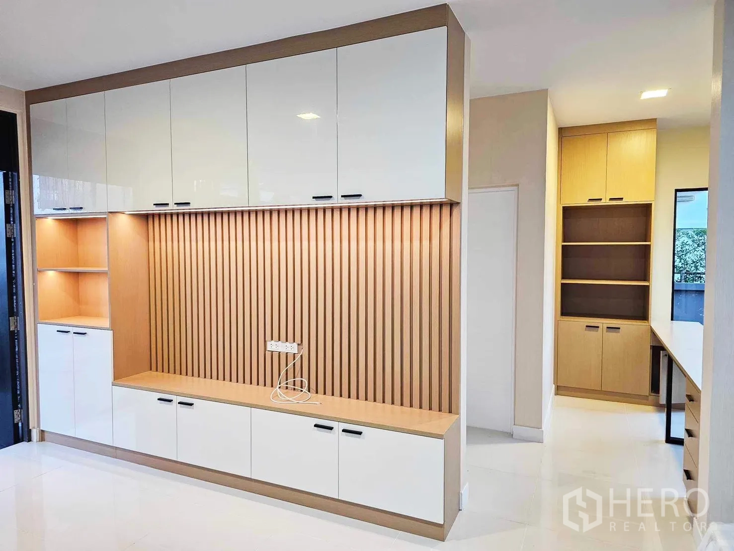 独栋房屋 for rent or sale in Prawet, Bangkok - 客厅内置电视墙，白木收纳柜与氛围灯光。