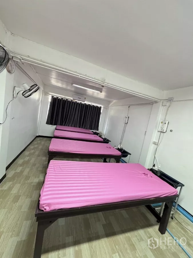 Shophouse for rent in Watthana, Bangkok - Treatment room with multiple massage beds lined up with pink covers.
