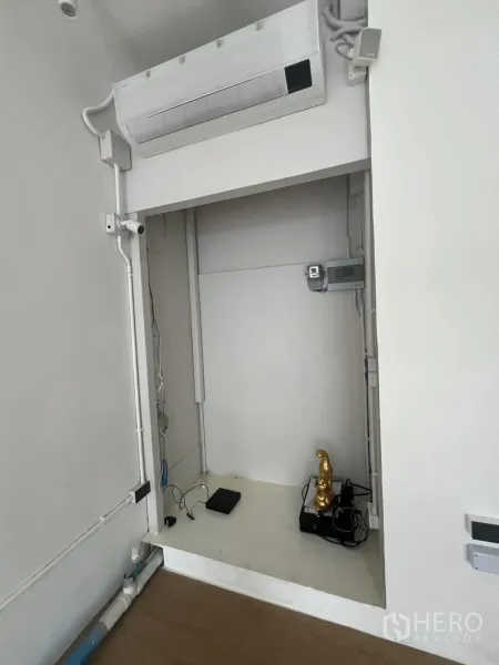 Retail Space for rent in Watthana, Bangkok - Service niche inside the shop with a wall-mounted air conditioner, visible electrical cabling and shelving.