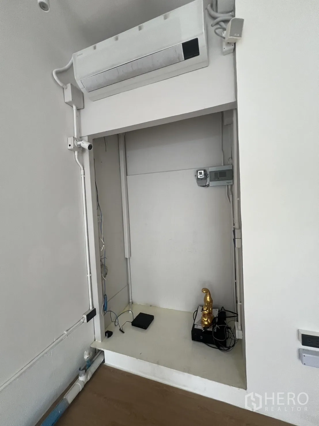 Retail Space for rent in Watthana, Bangkok - Service niche inside the shop with a wall-mounted air conditioner, visible electrical cabling and shelving.