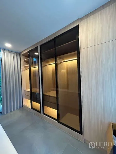 Detached House for rent in Saphan Sung, Bangkok - Close-up of illuminated glass wardrobes and wood-paneled storage.