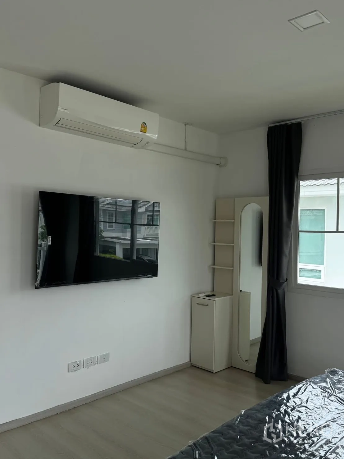 Detached House for rent in Bang Phli, Samut Prakan - Wall-mounted TV and air conditioner in a bedroom with a standing mirror.